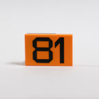 An orange 2x3 LEGO Tile photographed on a white background, with the number 81 printed in black.